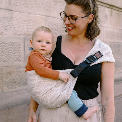 Didymos DidyHip Hüfttrage – Trias Creme Leinen – Person trägt Baby in heller gemusterter Hüfttrage
