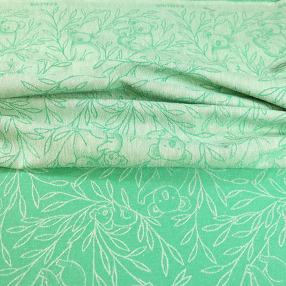 Didymos Puppentragetuch Koala Evergreen – Nahaufnahme des grünen Stoffes mit Koalamuster