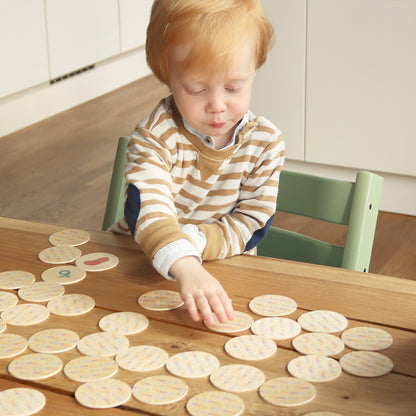 Kindsgut – Kind spielt mit runden Memo-Karten an einem Tisch