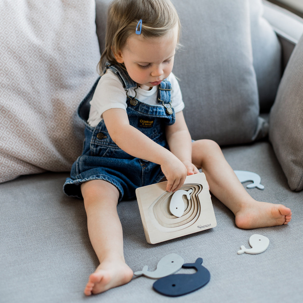 Kindsgut – Kind spielt mit den Walformen des Holzpuzzles