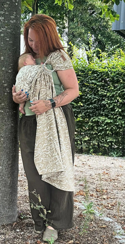 LELIBA Ring Sling – Ramus Rega – Person trägt Baby im hell gemusterten Ringsling