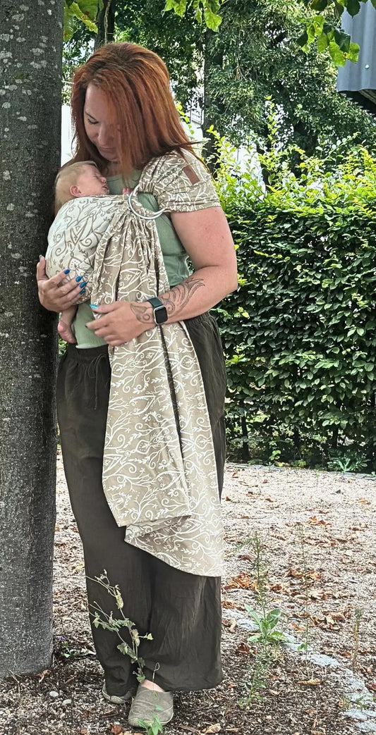 LELIBA Ring Sling – Ramus Rega – Person trägt Baby im hell gemusterten Ringsling