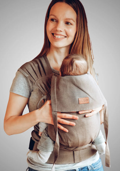 LELIBA Tai – Halfbuckle-Babytrage – Person trägt Baby in graubeiger Halfbuckle-Trage